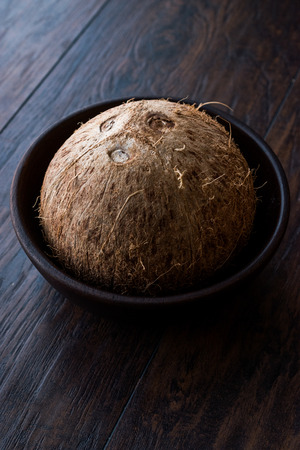 Fresh Organic Brown Raw Coconut in Dark Wooden Bowl. Organic Food.の写真素材