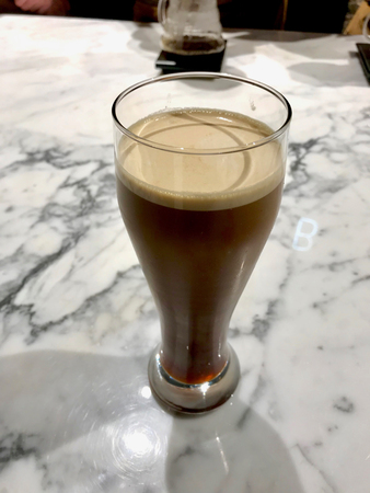 Glass of Nitro Cold Brew Coffee on Marble Surface Ready to Serve. Beverage Concept.