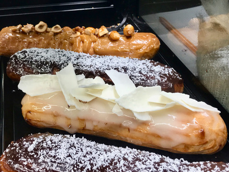 French Dessert Eclairs at Showcase of Cafe Shop. Traditional Sweet Food.