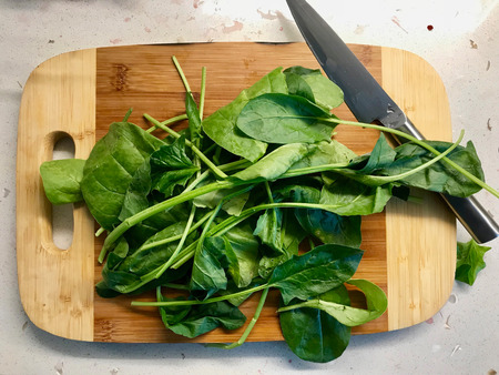 Baby Spinach Leaves Ready to Cut with Knife on Wooden Board. Ready to Useの写真素材