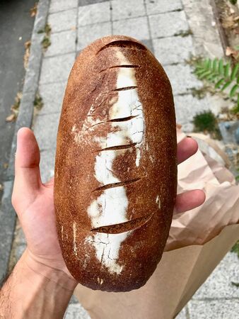 Einkorn Whole Wheat Bread Holding in Hand at Street. Organic Food.