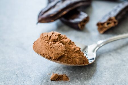 Carob Powder and Pods Ready to Use in Spoon. Organic Food.の写真素材