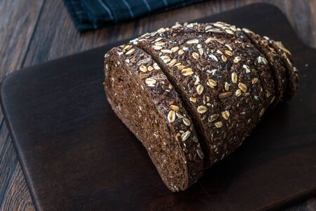 Malt Bread Slices with Oat and Flax Seeds on Dark Wooden Board. Organic Bakery Food.