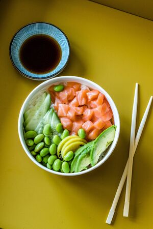 Hawaiian Poke Bowl with Salmon, Edamame, Takuan, Avocado, Cucumber Slices and Rice. Traditional...