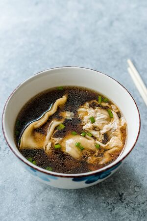 Asian Food Wonton Soup with Bok Choy and Chives in Porcelain or Ceramic Bowl. Traditional Dish Cuisine.の写真素材