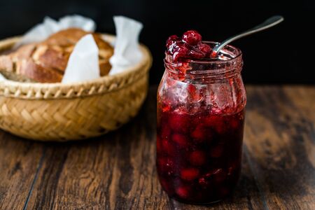Cranberry Jam in Jar with Spoon / Cranberries Marmalade served with Bread Slices in Wicker Bowl. Oraganic Food for Breakfast.の写真素材
