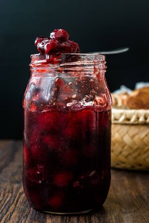 Cranberry Jam in Jar with Spoon / Cranberries Marmalade served with Bread Slices in Wicker Bowl. Oraganic Food for Breakfast.の写真素材