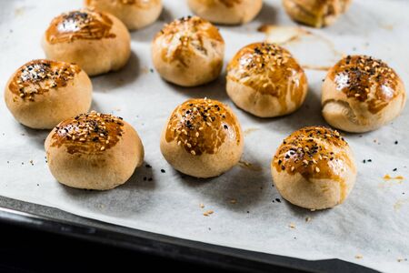 Homemade Turkish Pastries Pogaca with Black Cumin and Sesame Seeds on Baking Paper Sheet with Tray. Traditional Organic Food.の写真素材