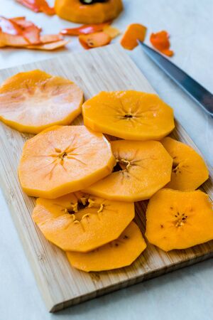 Sliced Persimmon Fruit Slices on Wooden Board with Knife. Organic Food.の写真素材