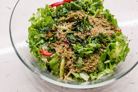 Homemade Salad with Herbal Sauce and Red Pepper Slices Mixed with Two Spoon in Glass Bowl. Organic Fresh Food.の写真素材