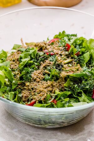 Homemade Salad with Herbal Sauce and Red Pepper Slices Mixed with Two Spoon in Glass Bowl. Organic Fresh Food.の写真素材