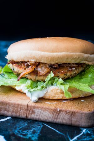 Homemade Salmon Burger with Tartar Sauce, Onion and Lettuce on Marble Board. Ready to Eat.の写真素材
