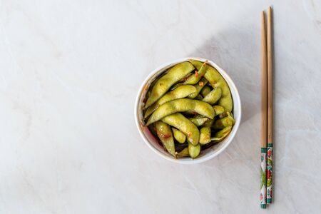 Healthy Take Away Asian Food Spicy Sambal Edamame with Chopsticks / Spiced Style with Red Hot Chili Sauce in Plastic Box Package / Container. Organic Food.の写真素材