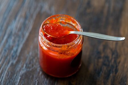Red Hot Chili Pepper Sauce for Artisan Cheese made with Vinegar and Sugar in Glass Bowl with Spoon. Organic Food.の写真素材