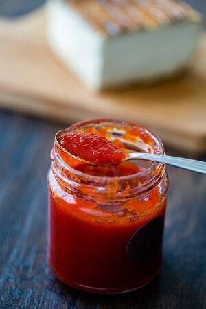 Red Hot Chili Pepper Sauce for Artisan Cheese made with Vinegar and Sugar in Glass Bowl with Spoon....
