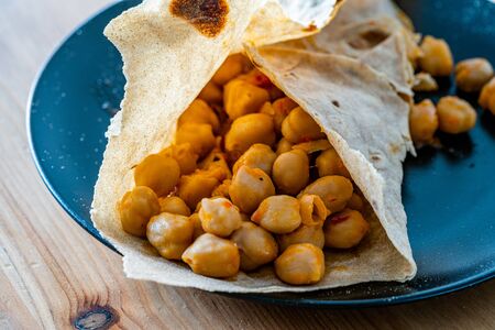 Tortilla Chickpea Wrap Samosa Buritto Ready to Eat with Natural Daylight on Wooden Table....