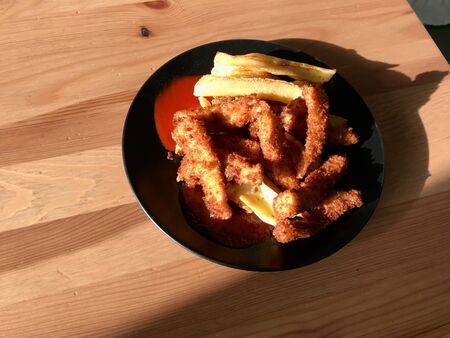 Fish and Chips made with Breaded and Fried Seabass in Black Plate. Fast Food.の写真素材