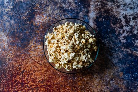 Caramel Popcorn in Glass Bowl on Grey Surface for Snack.