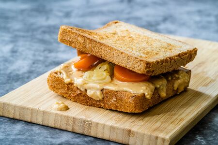 Organic Healthy Homemade Peanut Butter and Pickle Sandwich on Wooden Board. Ready to Eat.