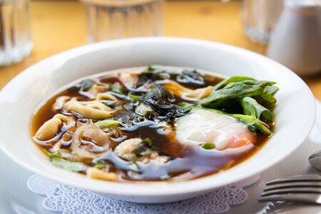 Asian Noodle Soup, Ramen with Poached Egg, Rocket Leaves, Onions and Various Vegetables served at Restaurant. Organic Traditional Food.の写真素材