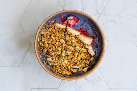 Blue Matcha Bowl with Granola, Blueberries and Banana / Healthy Blue Spirulina Smoothie in Brown Paper Kraft Carton Box. Organic Healthy Superfood.の写真素材