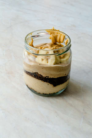Creamy Peanut Butter Pie Dessert with Banana Slice and Chocolate Cake in Jar / Paleo Diet Cup. Organic Healthy Homemade Food.の写真素材