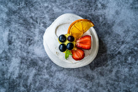 Meringue Dessert Pavlova Cake with Fresh Berries, Strawberries and Dried Orange Slice. Homemade Dessert.の写真素材