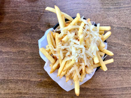 Street Food French Fries (Potatoes) with Parmesan Cheese and Truffle Sauce on Wooden Table at...