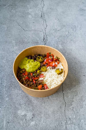 Take Away Traditional Mexican Tex-Mex Food with Minced Meat, Basmati Rice, Chicken and Guacamole Sauce in Take Out Plastic Bowl. Ready to Serve.の写真素材