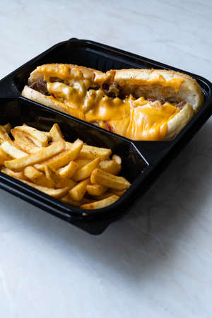 Take Away Philly Cheese Steak Sandwich with Melted Cheddar Cheese and Potatoes in Plastic Container...