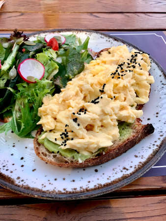 Scrambled Egg with Avocado Smash on Bread and Salad for Breakfast. Healthy Organic Food.の写真素材