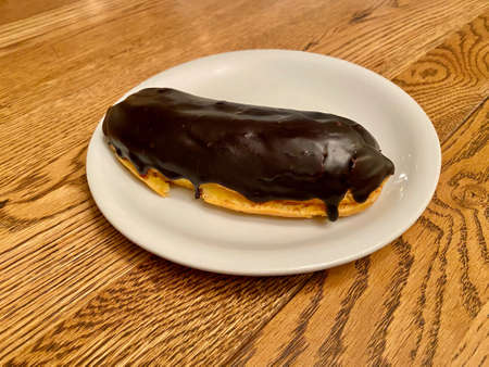 Chocolate Ã‰clair served in Plate at Restaurant Wooden Surface Table. Ready to Eat.