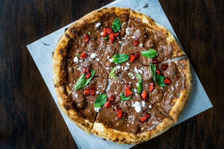 Sweet Pizza with Chocolate, Strawberries, Meringues and Mint Leaves on Dark Wooden Surface. Ready to Eat and Serve.の写真素材
