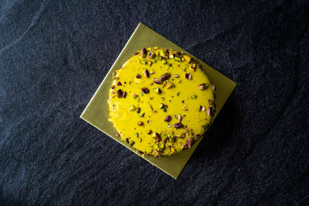 Edible Gold or Golden Covered Whole Pistachio Birthday Cake Ready to Serve and Eat on Stone Surface. Eatable Product.の写真素材