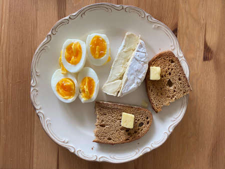 Breakfast Plate with Brie Cheese, Boiled Eggs and Butter Bread on Wooden Table. Ready to Serve and...
