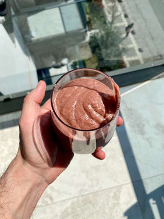 Refreshing Blackberry Smoothie with Avocado and Spinach Holding in Hand Outside Hot Sunny Weather. Ready to Drink.の写真素材
