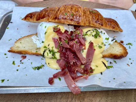 Croissant Sandwich with Poached Egg, Hollandaise Sauce and Sliced Roast Beef. Ready to Eat.