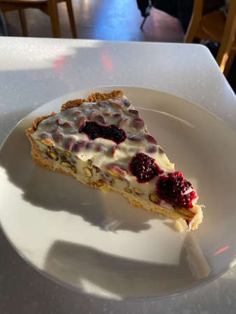 White Chocolate Tart Slice with Raspberry and Pistachio served with Plate at Cafe Shop Restaurant....