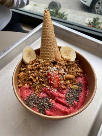 Red Smoothie Bowl with Ice Cream Cone or Cornet, Chia Seeds, Banana Slices and Granola. Ready to Eat