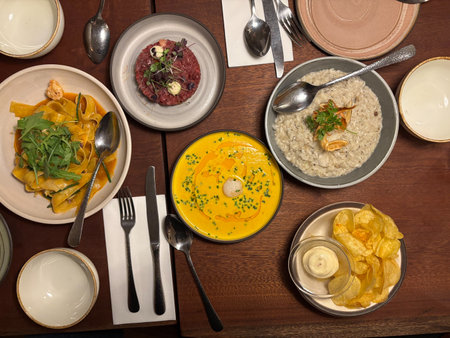 Dinner Table with Scallop Pumpkin Soup, Steak Tartare, Risotto and Chips. bird's eye view ready to...