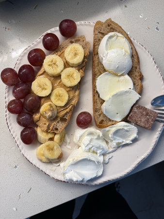 High calorie protein breakfast with peanut butter, banana, purple grapes, and cream cheese in plate