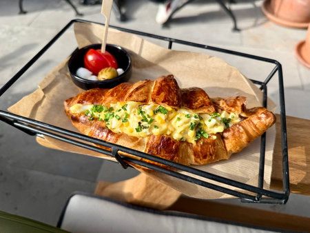 Croissant sandwich with scrambled egg at cafe shop in tray