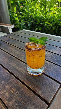 Chilli cocktail with tequila, mango and mint leaves on wooden table