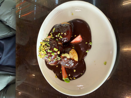 Delicious profiteroles with chocolate and white plate served at restaurant