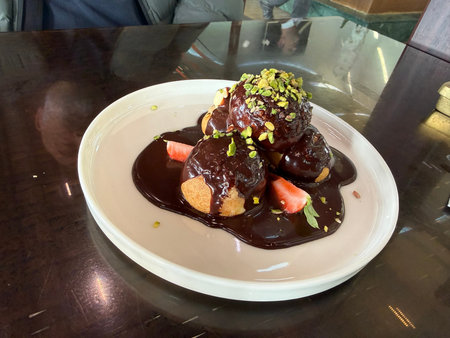 Delicious profiteroles with chocolate and white plate served at restaurant
