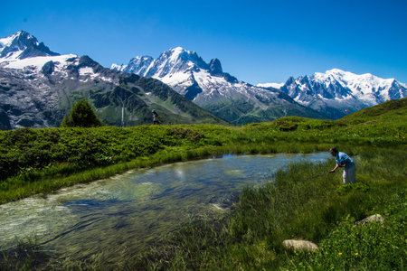 Mountain landscape with a river in the foreground and a hiker in the backgroundの写真素材