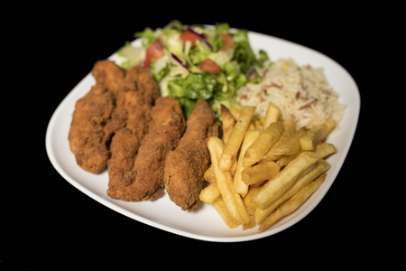 Chicken Goujons served with rice, salad and french fries on plate