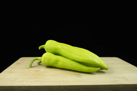 Fresh green peppers with banana shape on wood with isolated black backgroundの写真素材