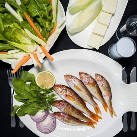 Fresh red mullet fishes with green salad, feta cheese, melon and Turkish alcoholic drink raki
