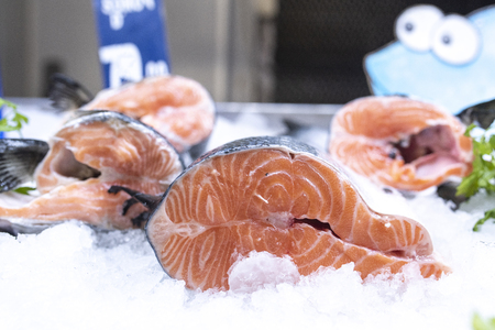 Fresh salmon fish on ice on seafood display at supermarketの写真素材